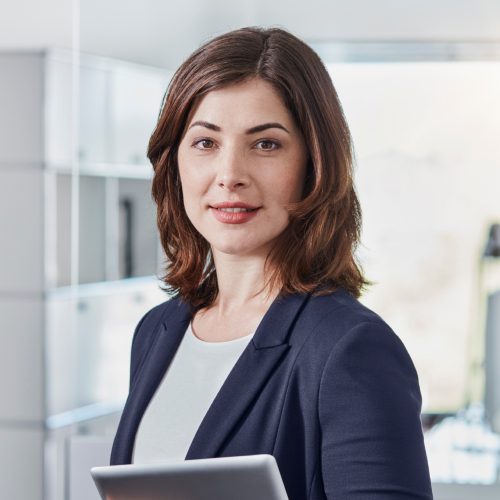 A woman standing in front of a window holding an ipad.