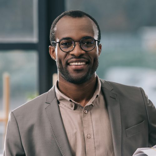 A man in glasses and a jacket smiling for the camera.