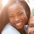 A woman smiles while hugging a man.