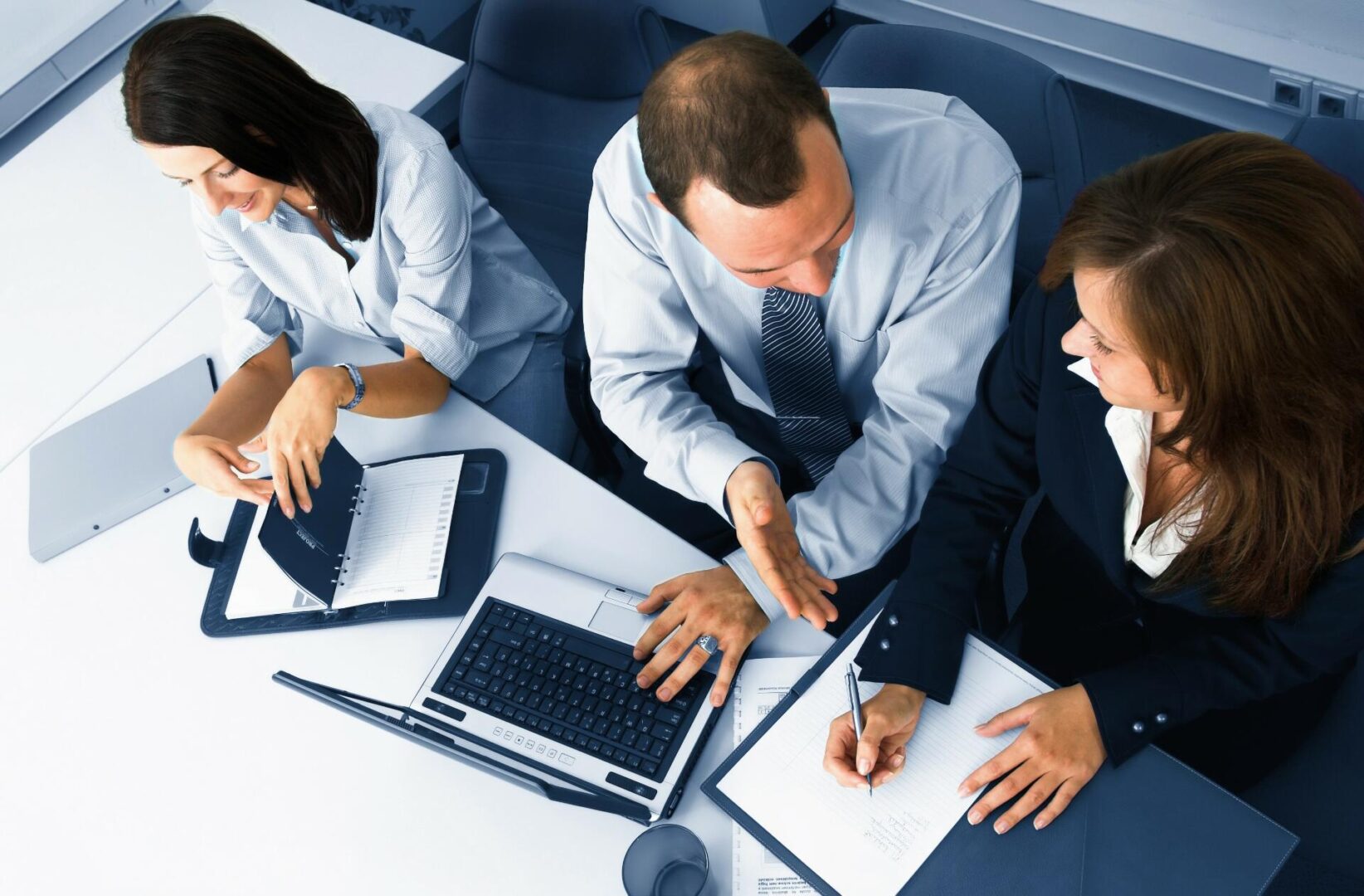 A group of people sitting at a table with laptops.