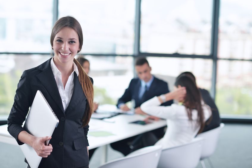 A woman in business attire holding papers while standing next to other people.