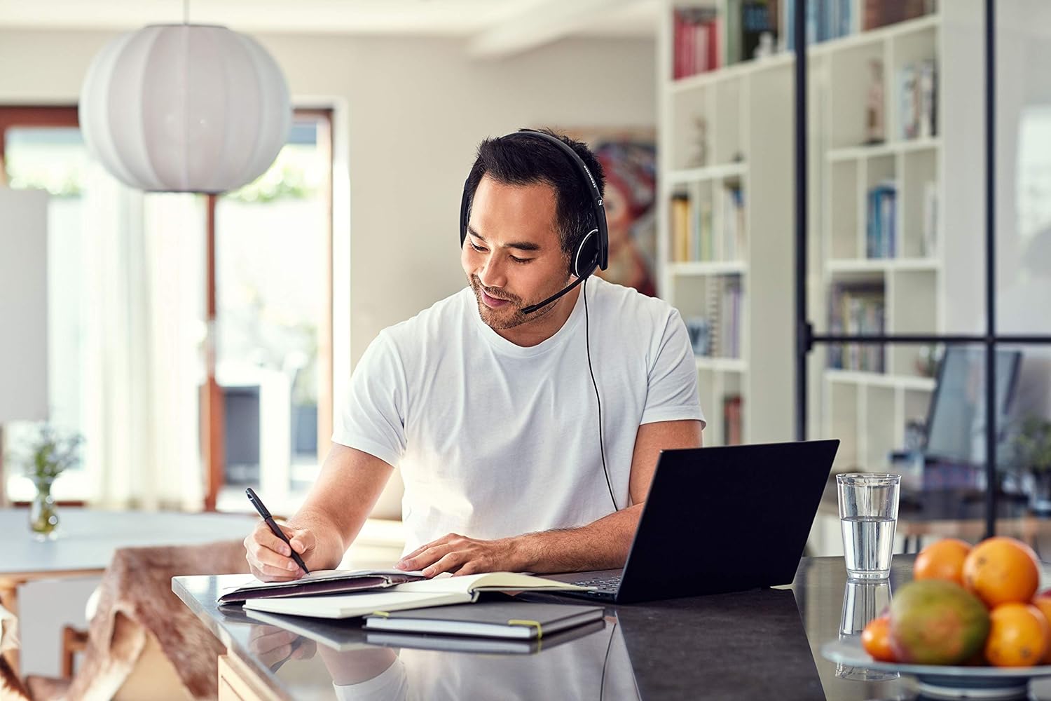 A man wearing headphones and writing on paper.