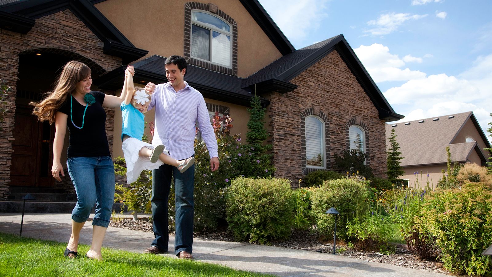 A man and woman walking down the sidewalk in front of a house.