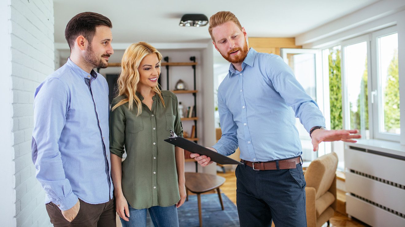 A man holding an ipad standing next to two women.