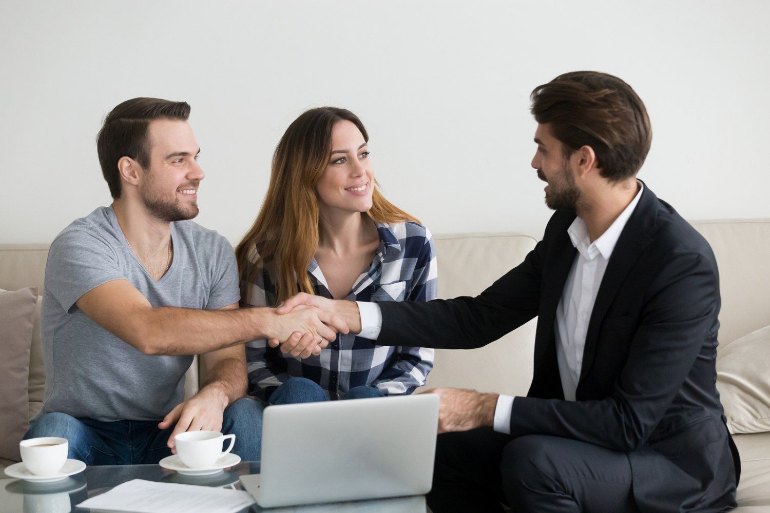 A man shaking hands with two women in front of him.