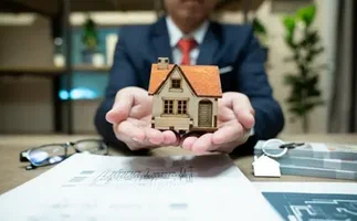 A man holding a small house in his hands.