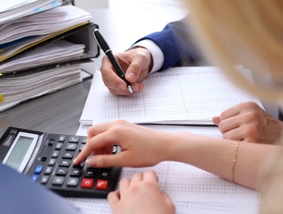 A person is working on some papers with a calculator.