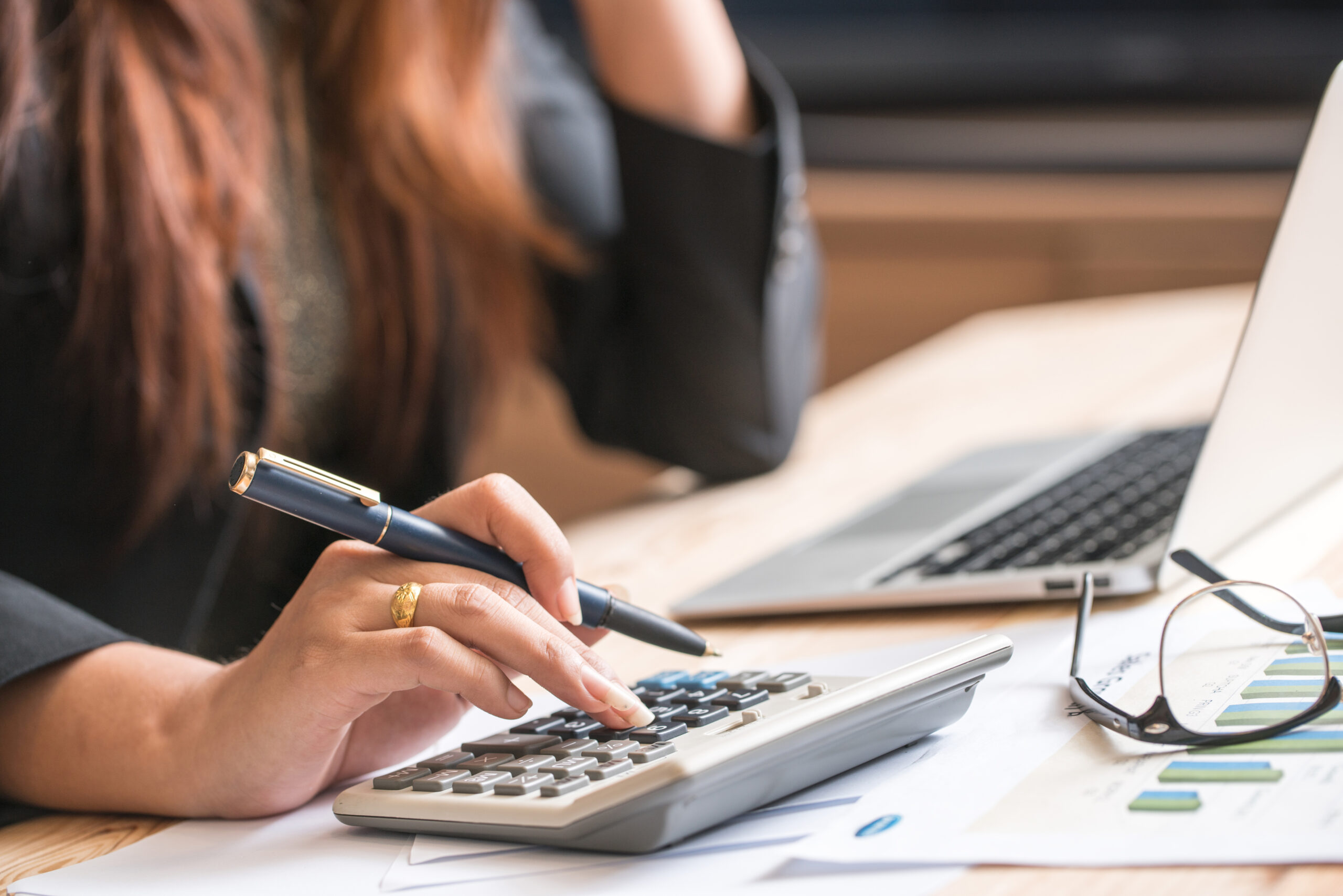 A woman using a calculator on top of papers.