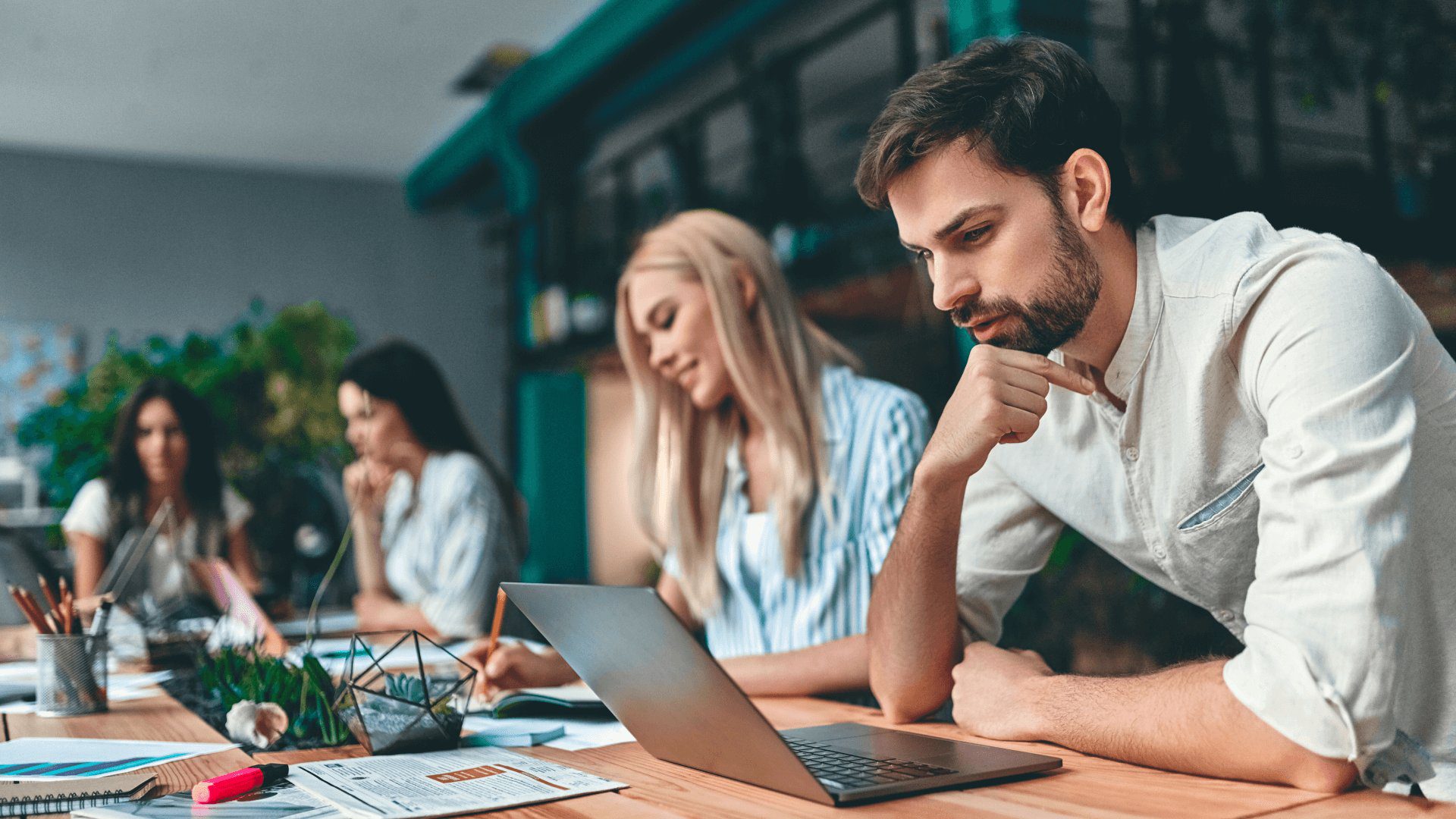 A group of people sitting at a table with laptops.